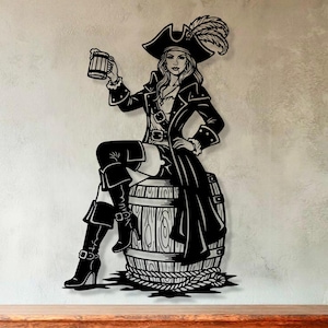 May include: Black metal wall art of a female pirate figure seated on a barrel, holding a mug. The pirate wears a hat with a feather, a long coat, and boots. The artwork is mounted on a light grey wall above a wooden cabinet.