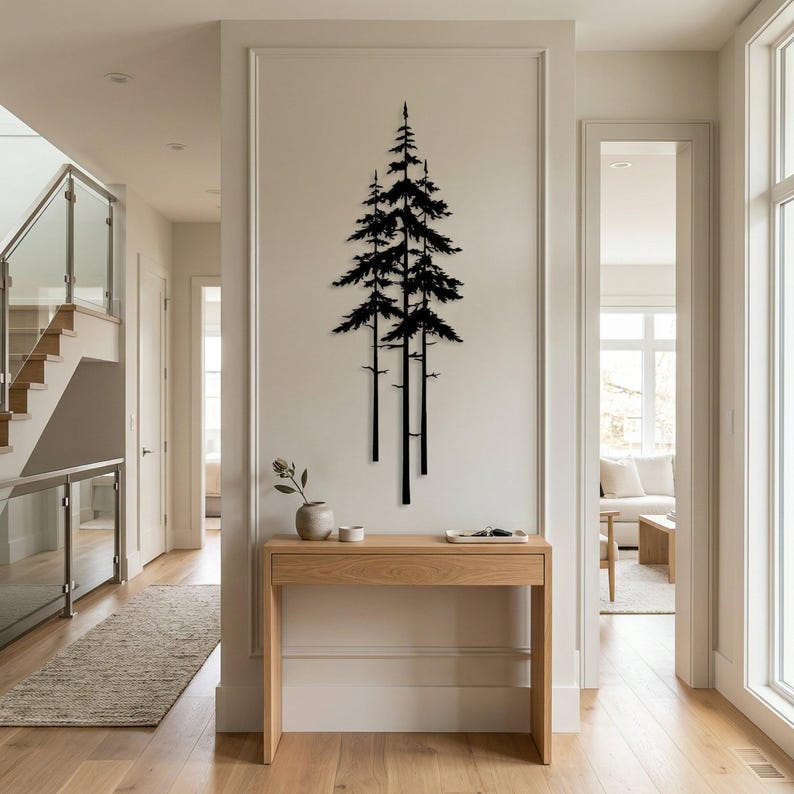 May include: A black metal wall art piece depicting three stylized pine trees. The artwork is mounted on a white wall in a well-lit hallway. A wooden console table with decorative items sits below the art.