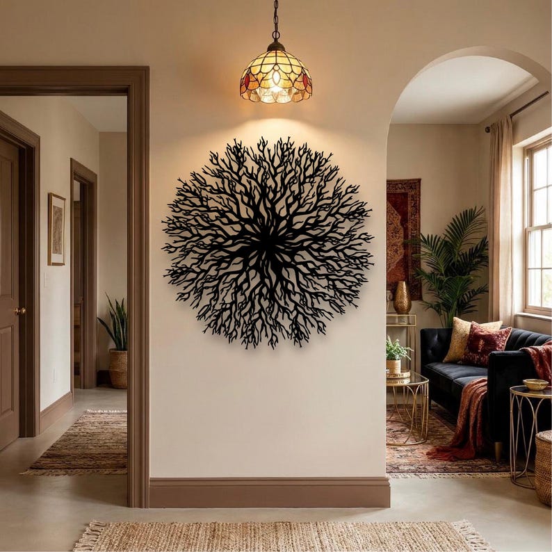 May include: A black metal tree-like wall art decorates a beige wall. A stained glass pendant light hangs above the art. The room has a neutral color palette with a rug and a sofa in the background.