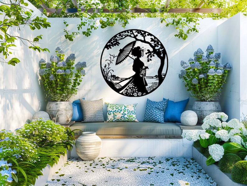 May include: A black metal wall decor featuring a silhouette of a woman holding an umbrella, standing in a garden setting. The decor is hanging on a white wall in a patio setting with lush greenery and potted plants.