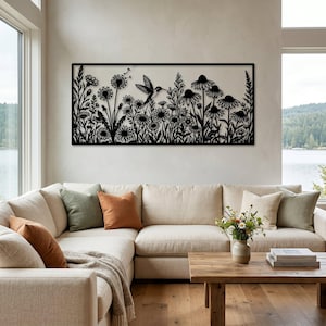 May include: A rectangular black metal wall art piece featuring a detailed silhouette of a hummingbird in flight surrounded by various wildflowers, including daisies and dandelions, all enclosed within a thin, solid black rectangular frame.