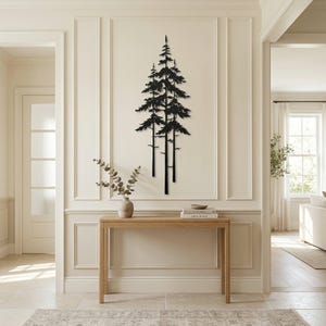 May include: Black metal wall art depicting three stylized pine trees. The artwork is mounted on a cream-colored wall, above a wooden console table. The room has a neutral color palette with natural light.