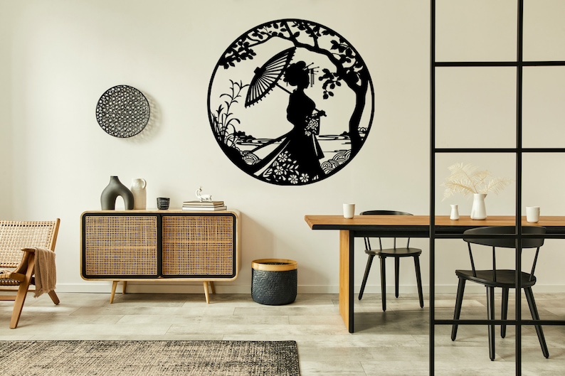 May include: Black metal wall art depicting a woman in a traditional Japanese kimono holding an umbrella, standing under a tree with flowers and leaves. The art is circular and has a detailed design.
