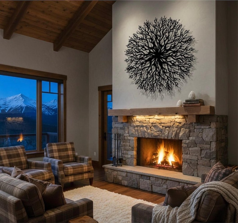 May include: A cozy living room with a stone fireplace and a burning fire. Above the fireplace is a wooden mantel and a large, circular, black metal wall art piece. The room has plaid furniture and a view of mountains through the window.