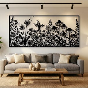 May include: A rectangular black metal wall art piece featuring a detailed silhouette of a hummingbird in flight surrounded by various wildflowers, tall grasses, and dandelion seed heads, all enclosed within a thin black rectangular frame.