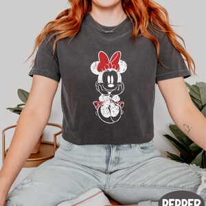 a woman with red hair wearing a mickey mouse t - shirt