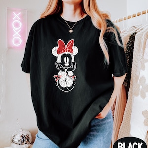 a woman wearing a black shirt with a minnie mouse graphic on it