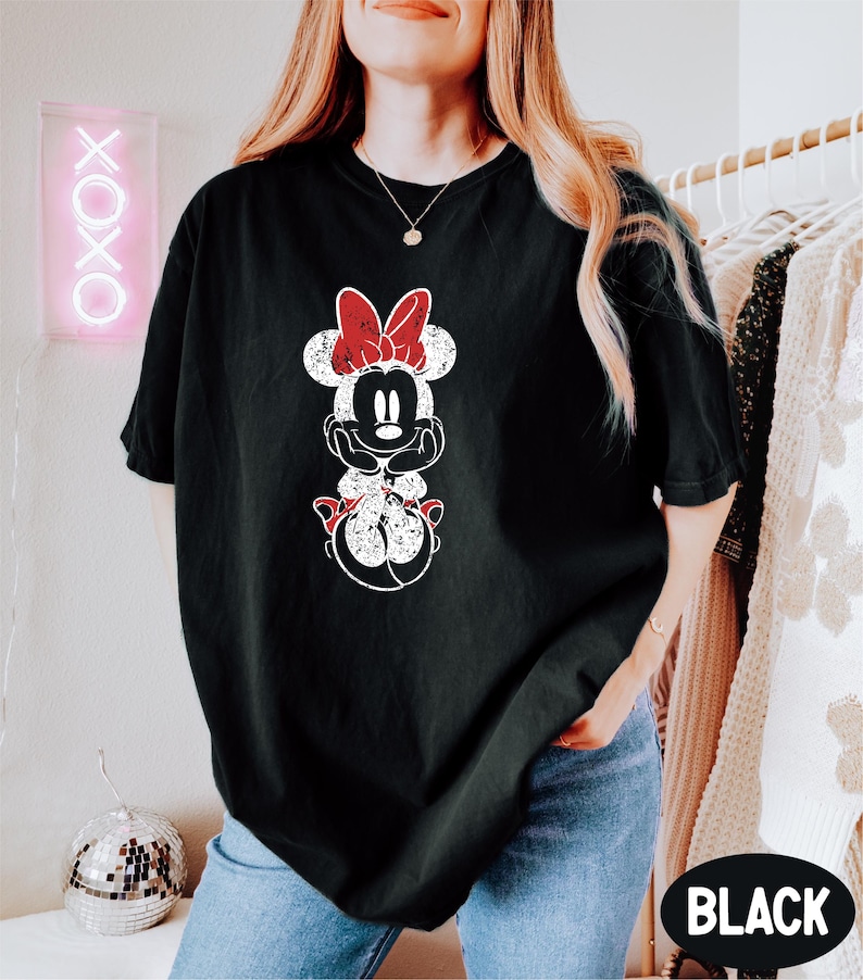 a woman wearing a black shirt with a minnie mouse graphic on it