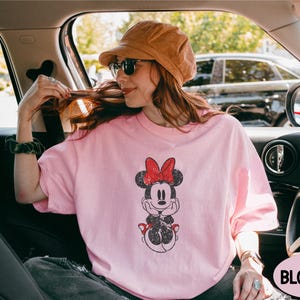 a woman sitting in a car wearing a minnie mouse shirt