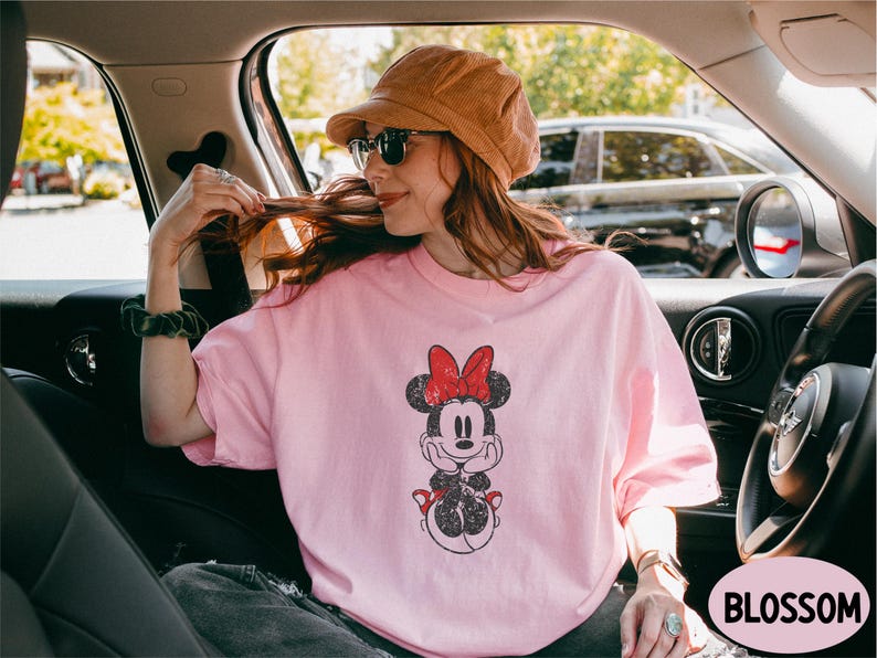 a woman sitting in a car wearing a minnie mouse shirt