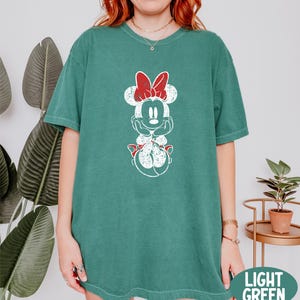 a woman wearing a green mickey mouse t - shirt