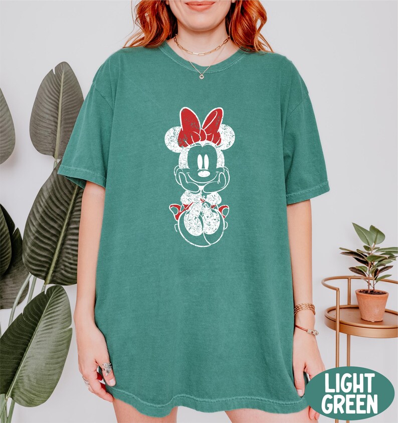 a woman wearing a green mickey mouse t - shirt