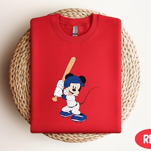 a red shirt with a mickey mouse holding a baseball bat