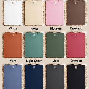 The image is a color chart displaying various comfort colors, including white, ivory, blossom, espresso, yam, light green, moss, Crimson, blue jeans, true navy, pepper, and black.