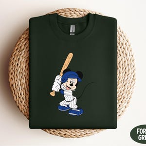 a green shirt with a mickey mouse holding a baseball bat