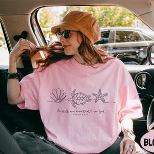 a woman in a pink shirt is sitting in a car