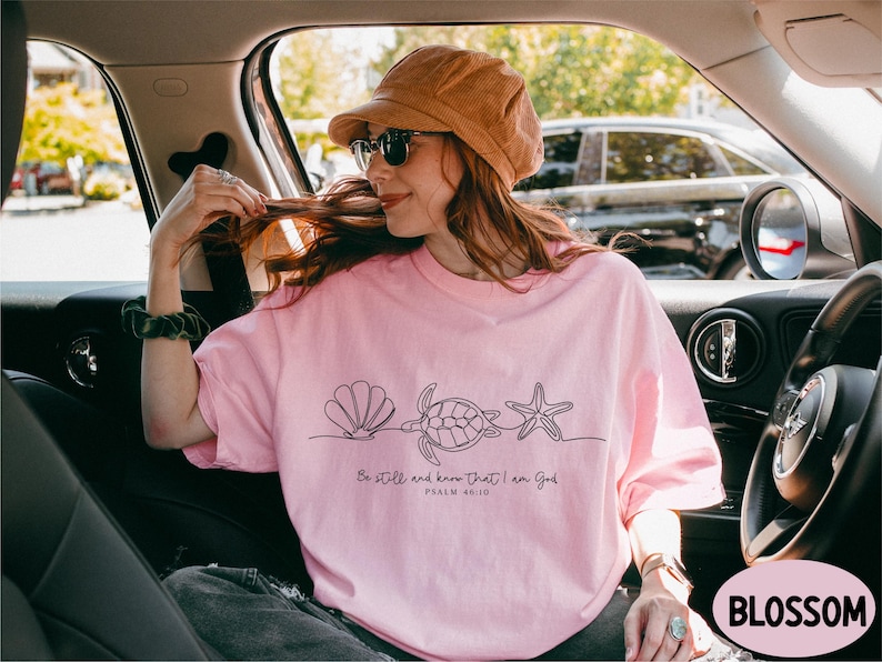 a woman in a pink shirt is sitting in a car