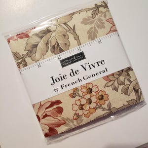 May include: A fabric bundle featuring a floral pattern in cream, pink, and brown tones. The fabric is packaged in a clear plastic bag and labeled "Joie de Vivre" by French General. A ruler is included.