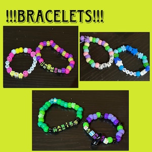 May include: Five colourful beaded bracelets with different words spelled out on them. The bracelets are made with small plastic beads and feature different colours, including pink, green, blue, yellow, and purple. The words on the bracelets are "Retro", "UR MOM", "FETUS", "MIKU", and "RABIES".