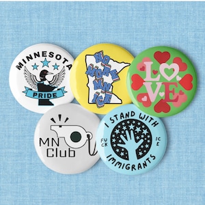 Puede incluir: Una colección de cinco botones redondos con varios diseños. Un botón presenta un somorgujo y el texto "Minnesota Pride". Otro dice "No More ICE". Otros botones dicen "LOVE", "MN Club" e "I Stand With Immigrants".