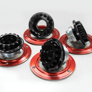 May include: Four black and silver central locking wheel nuts with red aluminum rings. The rings have the words "Centrallock" and "Losen/Remove" printed on them.
