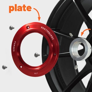 May include: A close-up of a wheel adapter kit with a red plate, a black nut, and a silver adapter. The plate is labeled "FORGED" and "CENTRAL LOCK".