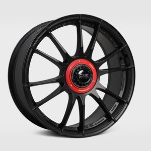 May include: Black alloy car wheel with a red center cap and OZ Racing logo. The wheel has a multi-spoke design.