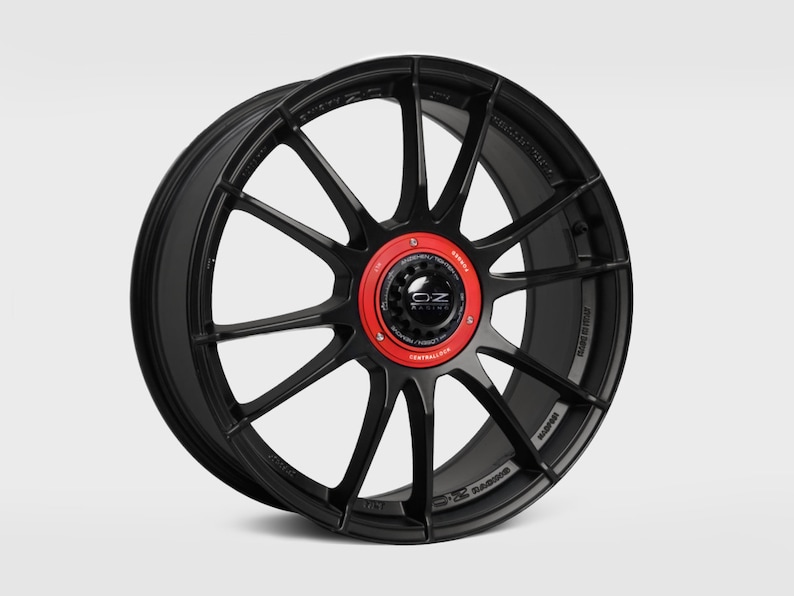 May include: Black alloy car wheel with a red center cap and OZ Racing logo. The wheel has a multi-spoke design.