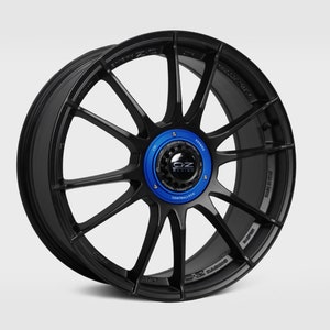 May include: Black OZ Racing alloy wheel with a blue center cap. The wheel has a multi-spoke design and is made of lightweight aluminum.