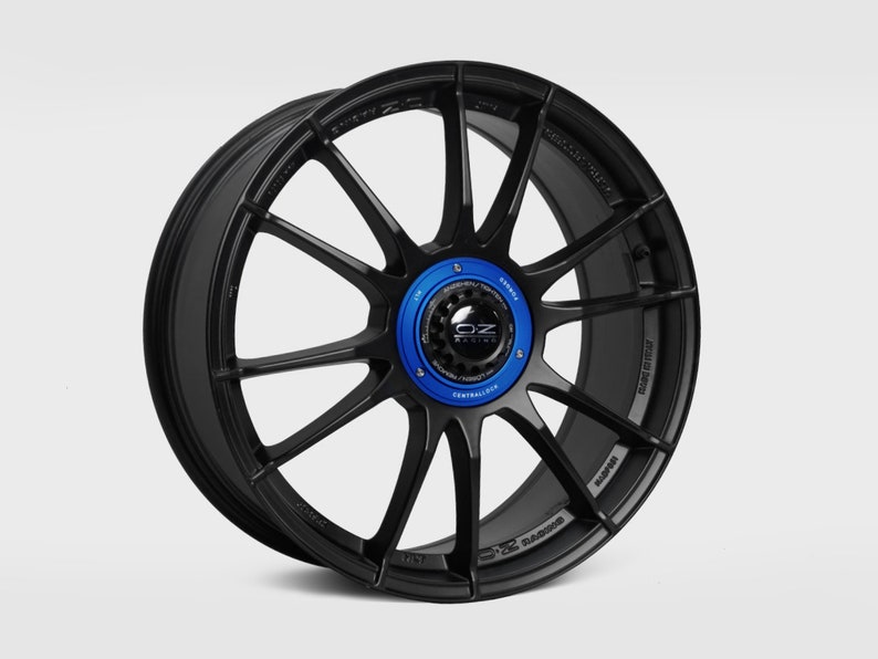 May include: Black OZ Racing alloy wheel with a blue center cap. The wheel has a multi-spoke design and is made of lightweight aluminum.