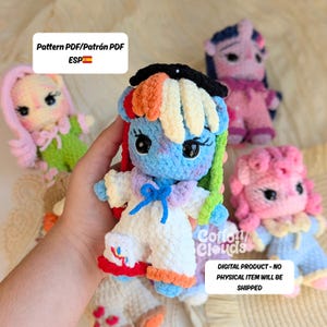 May include: A collection of colorful, crocheted pony dolls. The central doll is blue with a rainbow mane and white outfit. Other dolls include pink, purple, and yellow ponies. The image includes text that says "Pattern PDF" and "Digital Product - No Physical Item Will Be Shipped."