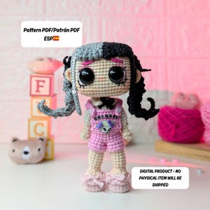May include: A handmade crochet doll with black and gray hair, wearing a pink overall with the text "CRY BABY". The doll has large black eyes and is wearing pink shoes. The image includes text that says "Pattern PDF" and "Digital Product - No Physical Item Will Be Shipped".