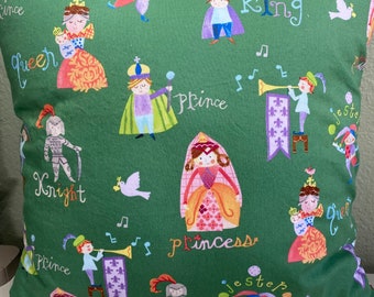 May include: A green pillowcase with a whimsical pattern featuring various characters from a fairytale. The characters include a king, queen, prince, princess, knight, and jester. The pillowcase is decorated with musical notes, birds, and other decorative elements.