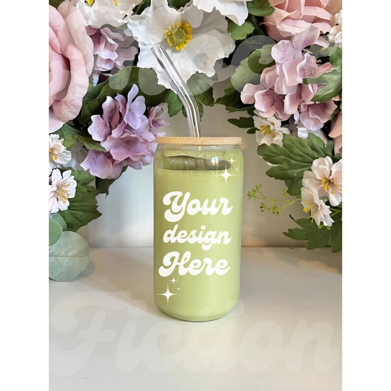 May include: A green glass can with a bamboo lid and a clear glass straw. The can has the text "Your design Here" in white on the front.