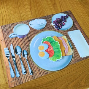 Op de afbeelding: Een ontbijtscene met een bord eten, een kopje koffie, een kom room en een bord druiven. Het eten op het bord bevat een sandwich met kaas, sla en tomaat, en twee helften van een hardgekookt ei.