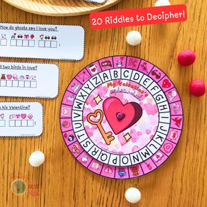 Op de afbeelding: Een roze en wit Valentijnsdag-cijferwiel met een hart- en sleutelontwerp. Het wiel heeft letters rond de rand en een draaiende pijl in het midden. De tekst "My Valentine's cipher wheel" is op het wiel gedrukt.
