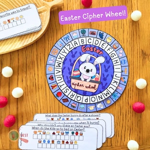 Puede incluir: Una rueda de cifrado de Pascua de color morado y azul con un conejito sosteniendo una cesta de huevos. La rueda tiene el alfabeto alrededor del exterior y una imagen de un conejito en el centro. Hay varias tarjetas con preguntas y cuadrículas de respuestas.