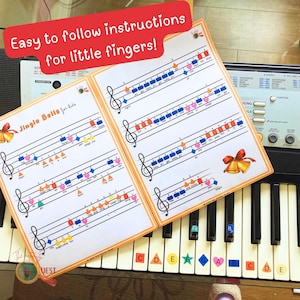May include: Two music sheets with colorful notes and the text "Jingle Bells for Kids" are placed on a keyboard. The sheets have an orange border and the text "Easy to follow instructions for little fingers!" is displayed above them.