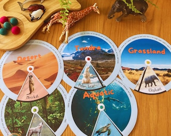 May include: Five colorful, circular learning cards with images of different animals and environments. Each card features a different biome: Desert, Tundra, Aquatic, Grassland, and Forest. The cards are labeled with the biome name and the animal featured on the card.