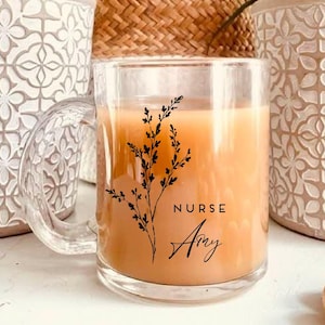 Pu&ograve; includere: Una tazza di vetro trasparente con un motivo floreale nero e il testo "NURSE Amy". La tazza &egrave; piena di un liquido marrone chiaro.