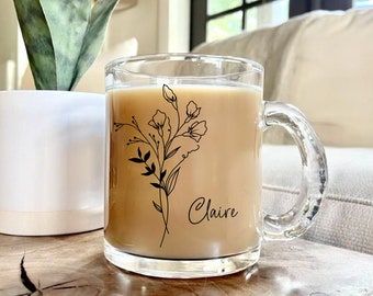 May include: A clear glass mug with a black floral design and the name "Claire" printed on the side. The mug is filled with a light brown beverage.