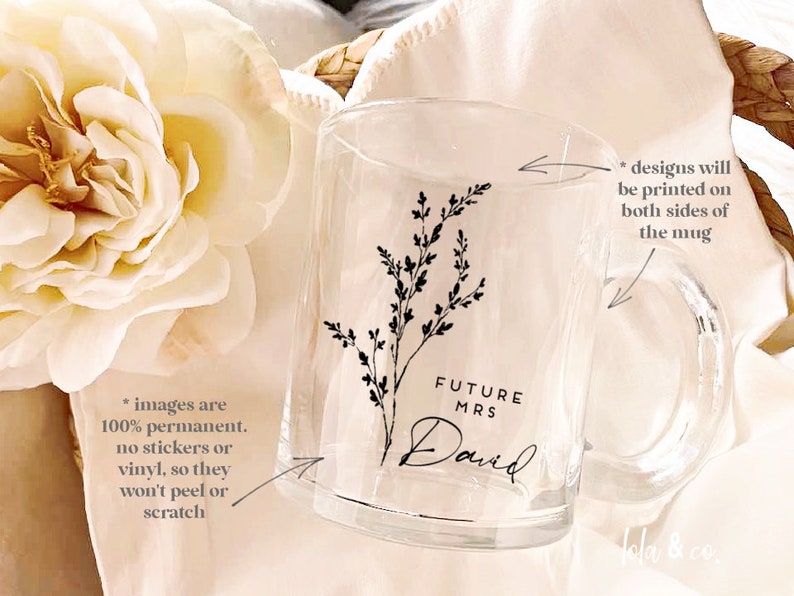 K&ouml;nnte beinhalten: Klare Glas-Tasse mit einem schwarzen Blumenmuster und dem Text "FUTURE MRS David". Die Tasse hat einen Henkel und das Design ist auf beiden Seiten bedruckt.