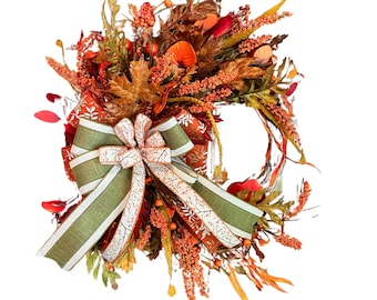 May include: A fall-themed wreath with a green and white ribbon bow. The wreath is decorated with faux leaves, berries, and flowers in shades of orange, red, and brown.