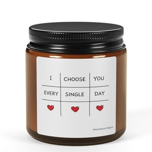 Puede incluir: Un tarro de vidrio marrón con tapa negra. El tarro tiene una etiqueta blanca con las palabras "I CHOOSE YOU EVERY SINGLE DAY" y tres corazones rojos. El tarro está lleno de una sustancia blanca.