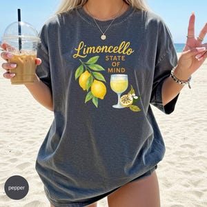 May include: Dark gray t-shirt with a "Limoncello State of Mind" graphic. The design features yellow lemons, green leaves, and a glass of limoncello. The shirt is a relaxed fit.