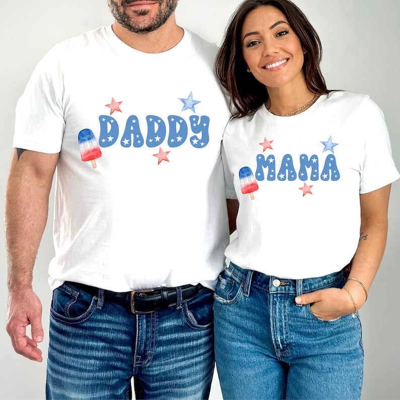 K&ouml;nnte beinhalten: Wei&szlig;e T-Shirts mit roten, wei&szlig;en und blauen Eis am Stiel-Grafiken und den Worten "Daddy" und "Mama" in Blau mit roten, wei&szlig;en und blauen Sternen.