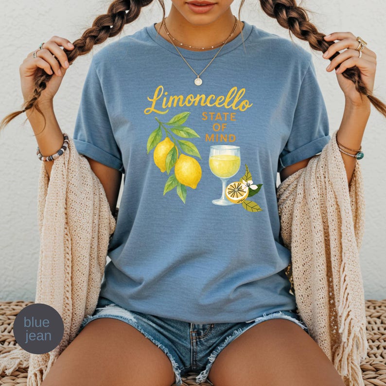 May include: Blue jean t-shirt with the words "Limoncello State of Mind" in yellow script. The shirt features a watercolor illustration of lemons, leaves, and a glass of limoncello.