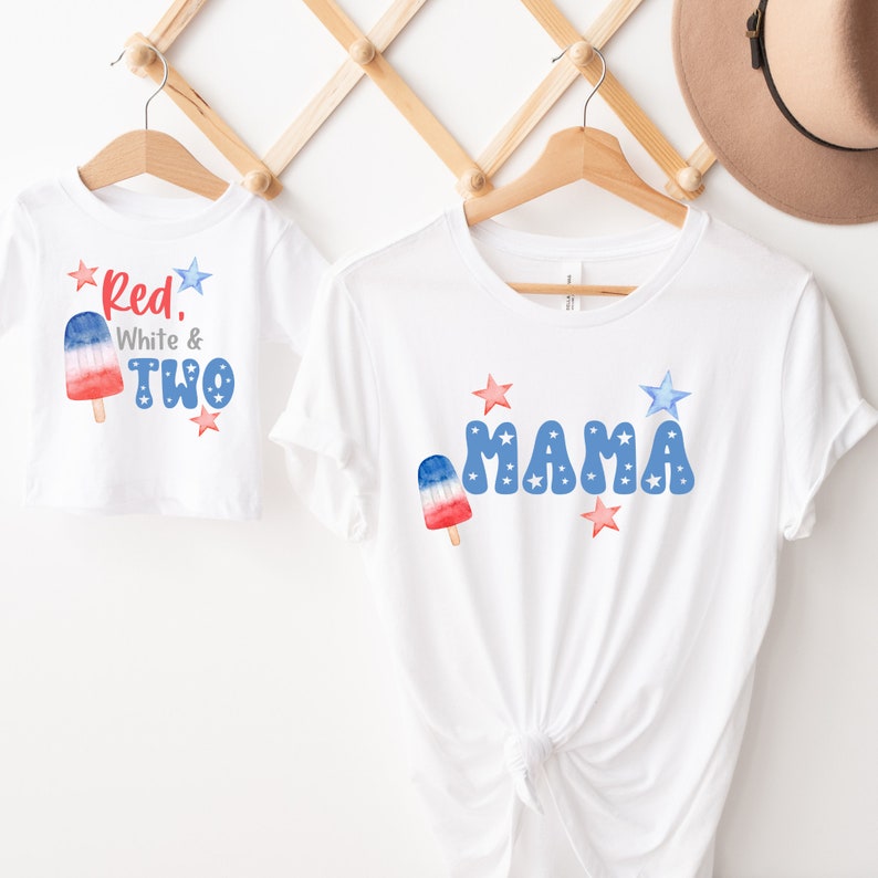K&ouml;nnte beinhalten: Zwei wei&szlig;e T-Shirts mit rot-wei&szlig;-blauen Grafiken. Ein Shirt sagt "Red, White & Two" mit einem rot-wei&szlig;-blauen Eis am Stiel. Das andere Shirt sagt "MAMA" mit rot-wei&szlig;-blauen Sternen und einem Eis am Stiel.