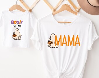 May include: Two white t-shirts with a ghost holding a pumpkin. The smaller shirt says "Boo! I'm Two!" and the larger shirt says "Mama".