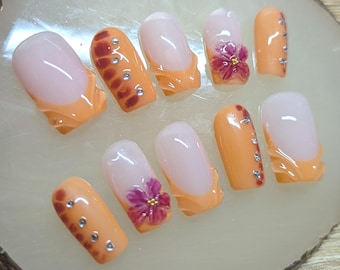 Uñas francesas naranjas: flores 3D, pedrería y diseño floral